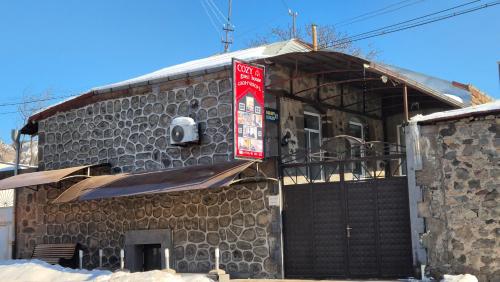 a stone building with a red sign on it at COZY guest hous Goris in Goris