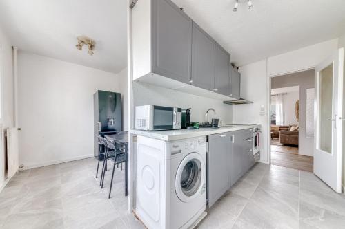 une cuisine avec un lave-linge et un micro-ondes dans l'établissement GuestReady - Bright near Parc Tête d’Or, à Villeurbanne