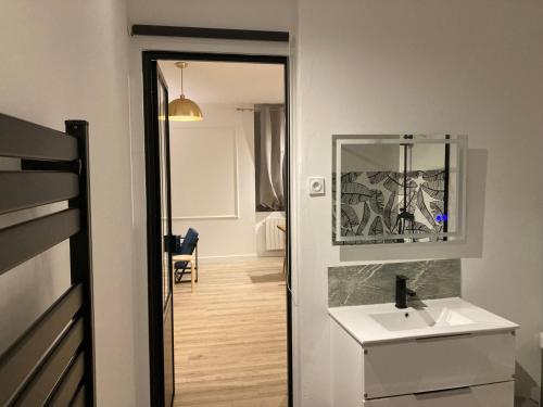 un bagno con un lavandino bianco e uno specchio di A5 Ecrin au premier étage a Évaux-les-Bains