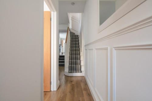 a hallway with white walls and wood floors at Spacious 3 Bedroom Home with PS5 and Pool Table Near O2 Arena Canary Wharf and Elizabeth Line to Central London in Woolwich