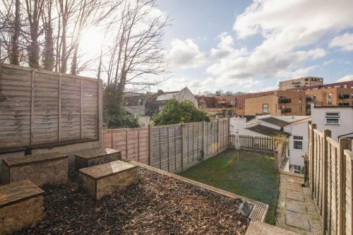 a backyard with a fence and a yard with benches at Spacious 3 Bedroom Home with PS5 and Pool Table Near O2 Arena Canary Wharf and Elizabeth Line to Central London in Woolwich