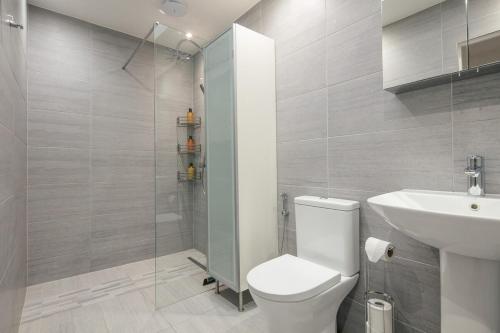 a bathroom with a toilet and a sink and a shower at Spacious 3 Bedroom Home with PS5 and Pool Table Near O2 Arena Canary Wharf and Elizabeth Line to Central London in Woolwich