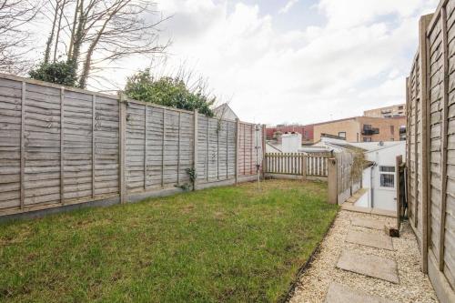 a backyard with a wooden fence and grass at Spacious 3 Bedroom Home with PS5 and Pool Table Near O2 Arena Canary Wharf and Elizabeth Line to Central London in Woolwich