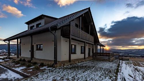 a house in the snow with the sunset in the background at wellness Chata u Pinkasů in Písečná