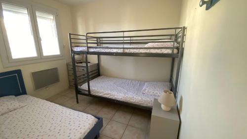 two bunk beds in a room with a window at Appartement Grand Large - 3 pièces - 5 couchages in Le Barcarès