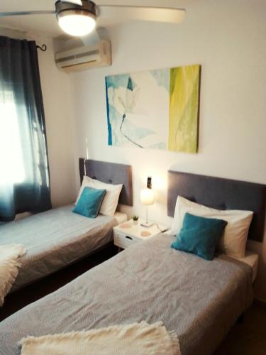 a bedroom with two beds and a painting on the wall at Casa Luna in Santiago de la Ribera