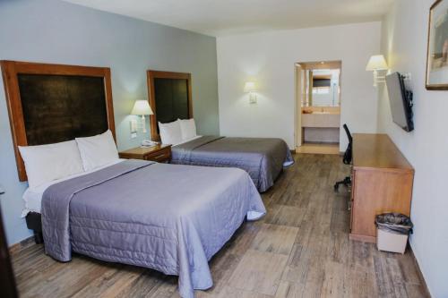 a hotel room with two beds and a desk at Hotel Villa del Sol in Ciudad Juárez