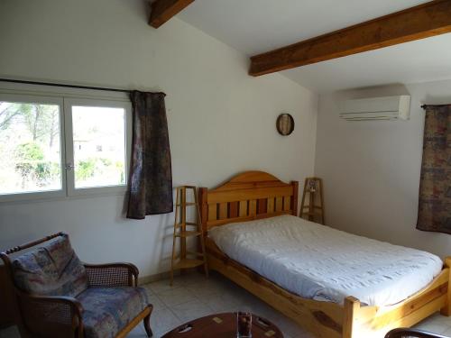 une chambre avec un lit, une chaise et une fenêtre dans l'établissement Longère de charme avec studio idépendant entre cèze et cevennes, à Saint-Ambroix