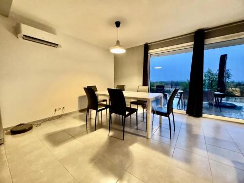une salle à manger avec une table et des chaises et une grande fenêtre dans l'établissement Maison lumineuse à Restinclières avec jardin et terrasse, à Restinclières