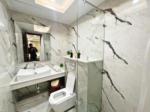 um banheiro com um vaso sanitário, uma pia e um espelho em Goldcrest Apartments em Lahore