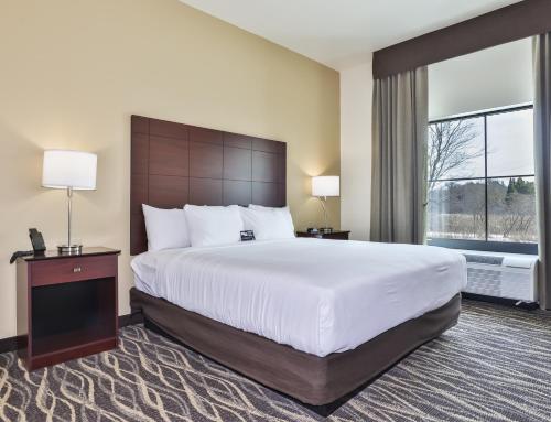 RhinelanderにあるCobblestone Hotel & Suites - Rhinelanderの大きなベッドと窓のあるホテルの部屋