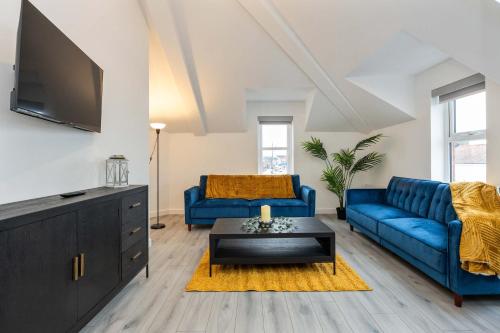 a living room with two blue couches and a tv at Unique 1 bed Penthouse in East Village, Belfast - Walk to City Centre, Roof Terrace in Belfast