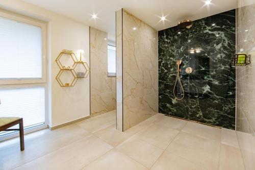 Un baño con ducha con pared de mármol negro. en Haus Marianne am Maar, en Schalkenmehren
