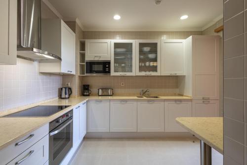a white kitchen with white cabinets and appliances at The Residences Vilamoura in Vilamoura