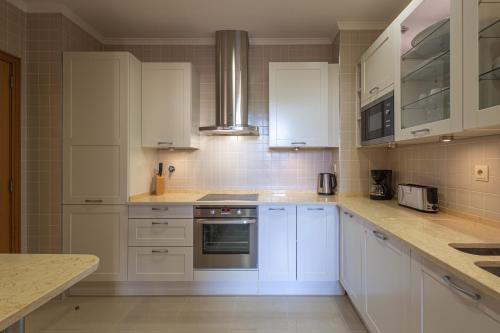 a white kitchen with white cabinets and appliances at The Residences Vilamoura in Vilamoura