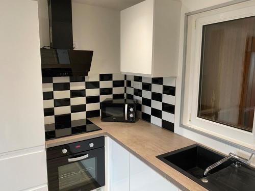 une cuisine avec un mur en damier noir et blanc dans l'établissement Petite maison chaleureuse, à Appoigny