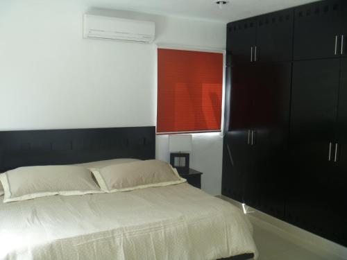 a bedroom with a bed with black cabinets and a window at Casa Mango in Valladolid