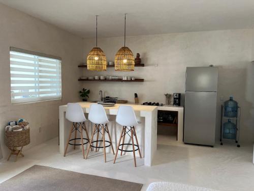 a kitchen with a counter with stools and a refrigerator at Villa Cayetano in Mahahual