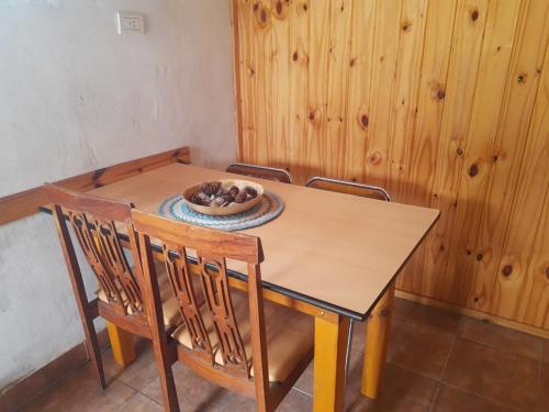 a wooden table with chairs and a bowl of fruit on it at Altos del Peñón Cabañas in Casa Grande