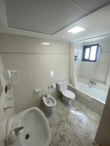 a bathroom with a sink and a toilet and a bath tub at Hotel Posada del Mar Playa de Gandía in Puerto de Gandía