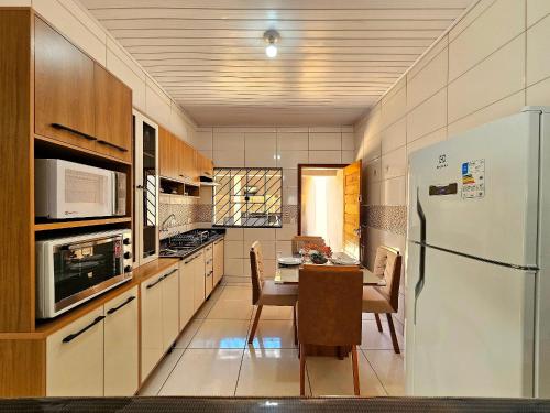 a kitchen with a table and a refrigerator at Casa 3quartos sinuca prox Paraguai e Itaipu in Foz do Iguaçu