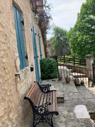 un banc en bois assis devant un bâtiment dans l'établissement Wisteria House, à Douzillac