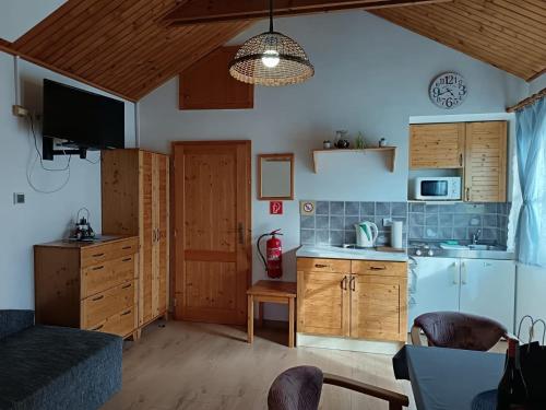 a kitchen with wooden cabinets and a table with a microwave at Tatralandia Chatka SnoWiki in Liptovský Mikuláš