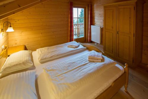 a bedroom with two beds in a log cabin at Feriendorf Koralpe Chalet Koralmrose in St. Gertraud