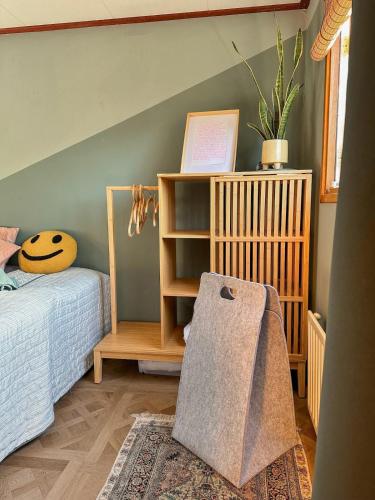 a bedroom with a bed and a shelf with a potted plant at Uniek boshuisje Olijfje met omheinde tuin op loopafstand Veluwse bos in Putten