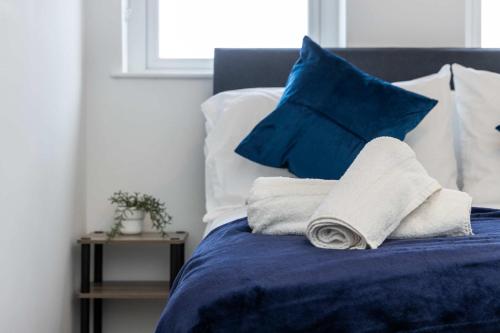 a bed with blue pillows and towels on it at Stunning 1 bed Penthouse Apartment in East Village, Belfast - Walk to City Centre, Roof Terrace in Belfast