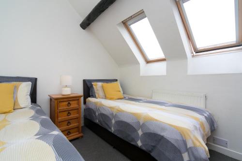 two beds in a room with two windows at Harrison's Cottage in Llandegla