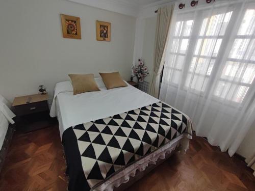 Schlafzimmer mit einem schwarzen und weißen Bett und Fenstern in der Unterkunft La culta elegante in Sucre