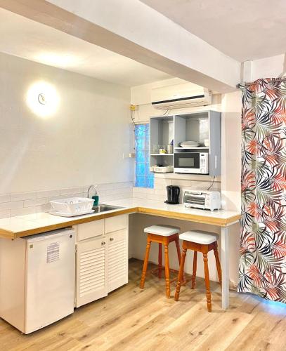 a kitchen with a counter and two stools in it at Bananaquit Tobago -Stay Near the Beach in Crown Point