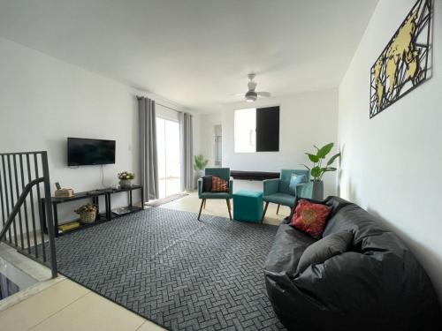 a living room with a black leather couch and chairs at Apartamento Duplex in Uberaba