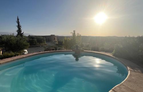 a swimming pool with the sun in the background at Les Jardins de la Santé in Tamazouzte