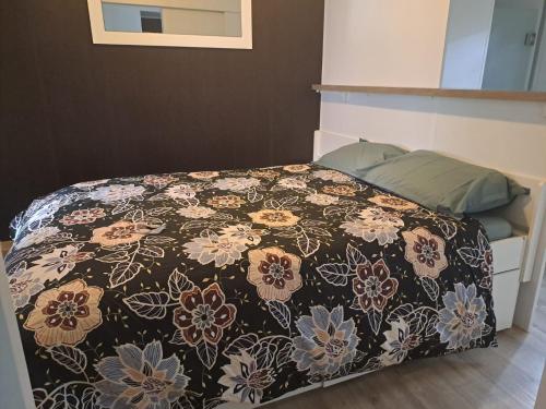 AzurLandes Azur mobil home 38 m2 7km de vieux boucau的一张床上的黑色毯子,上面有鲜花