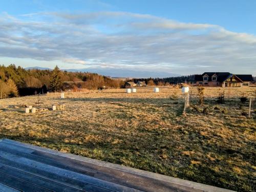 a view of a field with a house in the background at Przewietrzona Głowa in Ponikwa