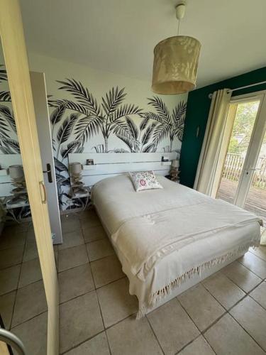 une chambre avec un lit avec un papier peint tropical dans l'établissement Maison esprit cabane proche océan et bassin, à Lège-Cap-Ferret