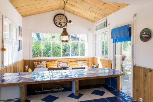 Cette grande chambre dispose d'une table et d'une horloge murale. dans l'établissement Maison esprit cabane proche océan et bassin, à Lège-Cap-Ferret