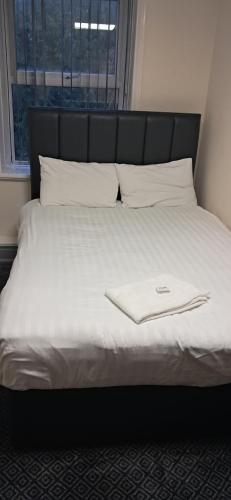 a bed with a black headboard and white sheets and pillows at Park hotel in Bradford