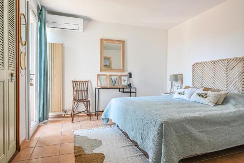 a white bedroom with a bed and a chair at villa les nefliers vue panoramique mer et plage à pied in Cassis