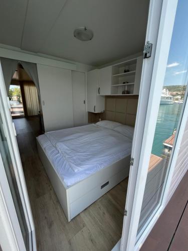 Bett in der Mitte eines Zimmers mit Fenster in der Unterkunft Marina Luxury Houseboat Lace in Portorož