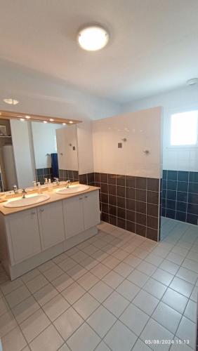 une salle de bain avec deux lavabos et un grand miroir dans l'établissement Grande maison 100m2 7 personnes 3 chambres, à Bretignolles-sur-Mer