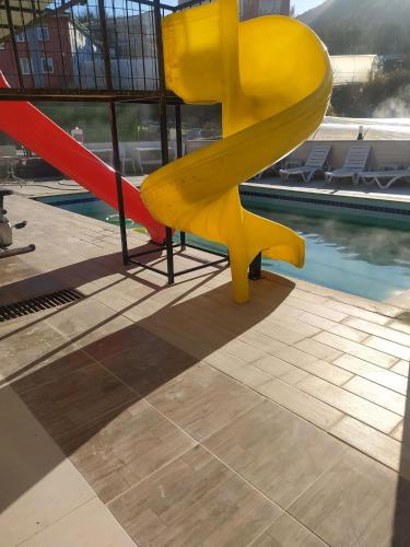 a yellow slide in front of a swimming pool at sanita otel in Bayramşah