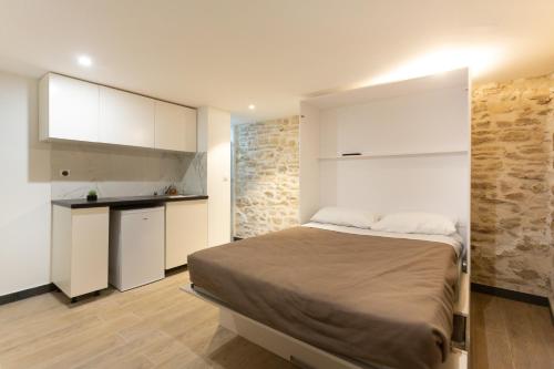 a small bedroom with a bed and a kitchen at Hôtel Léonard de Vinci II in Paris