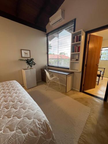 a bedroom with a bed and a desk and a window at Pariká Pousada in Alto Paraíso de Goiás