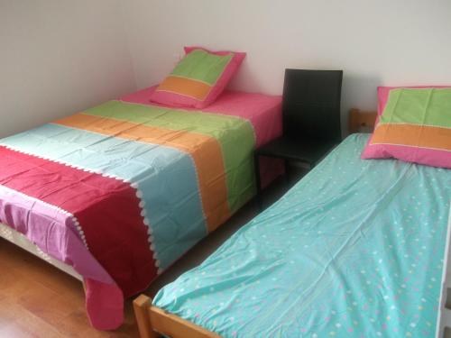 Cette chambre comprend 2 lits avec des draps colorés et une chaise. dans l'établissement Grande maison 100m2 7 personnes 3 chambres, à Bretignolles-sur-Mer