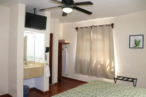 a bedroom with a bed and a ceiling fan at HOTEL CASA DE LAS PALOMAS in Tonalá