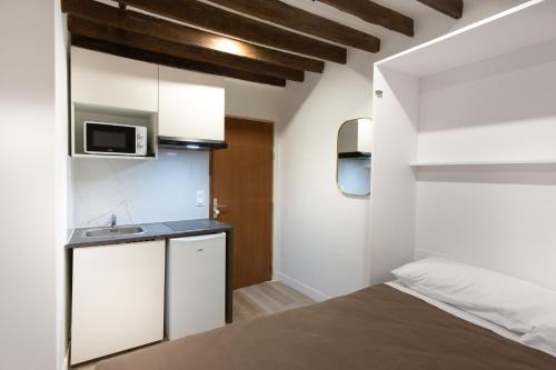 a small bedroom with a bed and a microwave at Hôtel Léonard de Vinci II in Paris