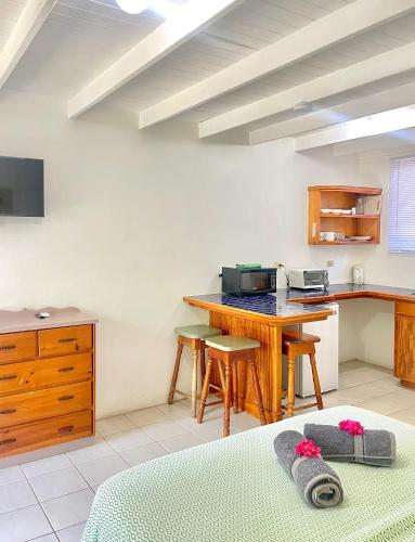 a kitchen with a counter and a table with stools at Bananaquit Tobago -Stay Near the Beach in Crown Point